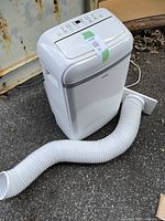 Front view of KoolKing portable air conditioner connected to exhaust hose and window insert