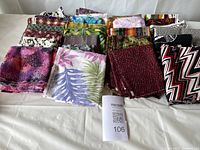 Photo showing multiple folded pieces of cotton fabric with various colorful patterns including leaves, zigzags, florals, and abstract designs.