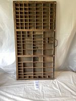 Full front view of vintage wooden printer's drawer showing multiple compartments and patina.