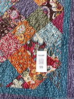 Close-up photo showing the patchwork fabric squares and quilting stitches on the quilt