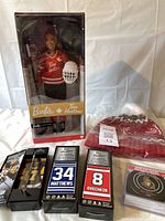 Tim Hortons Barbie doll in original packaging with red jersey and helmet, three mini hockey sticks boxed, four Ottawa Senators puck coasters packaged, and red and white knit winter hat with pompom and tag.