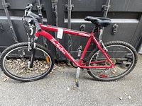 Side view of red Tim Hortons branded Raleigh bicycle with black seat and off-road tires, showing overall condition and visible rust on frame and parts.