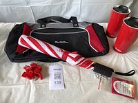 Overview of Tim Hortons duffle bag, two red ceramic travel mugs, red and white striped umbrella, and four red plastic whistles on white surface.