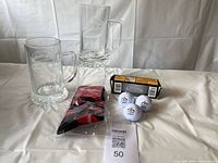 Two clear glass steins with Tim Hortons logo, packaged Tim Hortons coffee cup socks, three Callaway golf balls, and Callaway golf ball box.