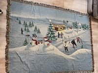 Photo of Tim Hortons branded blanket laid flat showing detailed winter hockey game scene with snowmen and pine trees.
