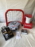 Full lot showing a mini hockey net, three boxed mugs, Sidney Crosby puzzle, toy Zamboni, mini hockey sticks, and puck coasters.