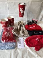 Full lot including all mugs, hats, scarves, mittens, and coasters displayed on table