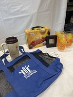 Photo of Tim Hortons lot items including travel mug, Timbits lunchbox, plastic cups, commemorative clock, and blue beach bag