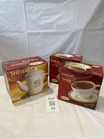 Three boxed Tim Hortons teaware items: one ceramic teapot in a red and yellow box, and two ceramic teacup and saucer sets in red boxes, all with Tim Hortons branding.