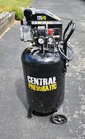 Front view of the upright black Central Pneumatic air compressor showing the brand name, pressure rating, horsepower, and tank capacity stickers.