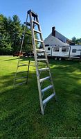 Full view of the Werner aluminum ladder standing open on grass outdoors.