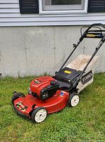 Side view of red Toro mower on grass with bag attached