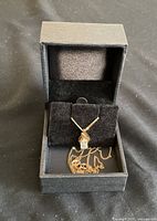 Black jewelry box open displaying the gold chain and pendant.