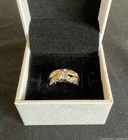Wedding ring set displayed in a white box with black interior, showing the engagement-style ring with a large central stone.