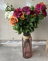 Photo of the first artificial flower stick showing white, orange, dark red, and purple roses with green leaves on green stems inside a pinkish decorative vase (vase not included in sale).