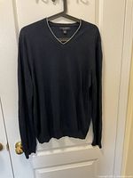 Front view of dark blue V-neck silk linen pullover on hanger