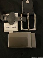 Two new Perry Ellis belt buckles, one traditional buckle and one clip style, shown clearly with brand tags.