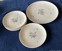 Top view of 5 small cake plates stacked with 1 large serving plate on blue fabric background