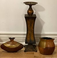 Photo of tall wooden candle stand centered between two decorative wooden vases with varied wood textures and finishes.