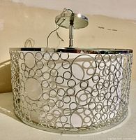 Side view showing wide circular metal ring cage design with open pattern in chrome finish