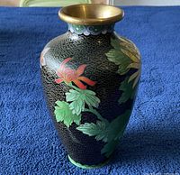 Front view of cloisonné vase featuring large red and yellow flowers with green leaves on black background with gold wire pattern, brass rim visible.