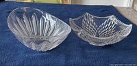 Two clear crystal bowls on a blue cloth, one with vertical elongated cuts and one with leaf-like pattern