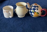 Photo of ceramic cup with snowflakes, cream-colored vase, and decorative teapot