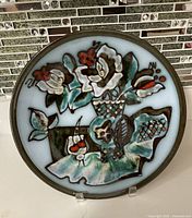 Front view of one decorative plate with floral design on light blue background, showing vibrant hand-painted style.