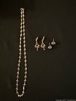 Full lot display of necklace and two pairs of earrings on black background