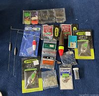 Top view of lot showing tackle box, fishing floats, lure packs, hooks, and sinkers on blue cloth