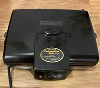 Top view of black Hamilton Beach electric grill with removable dishwasher safe grids label on front.