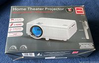 Box of RCA Home Theater Projector showing product image and key features like up to 150" picture size, 2 HDMI inputs, 50,000 hour lamp life, 1080p compatible resolution.