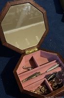 Open octagonal wooden jewellery box showing three tie clips stored inside.