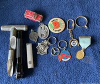 Photo of assorted key rings and small items arranged on a blue fabric background.
