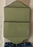 Front view showing the green metal mail/letter box with two compartments and three hooks at the bottom.