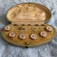 Closed original fitted case holding 8 gilt buttons and 6 button loops for men's clothing