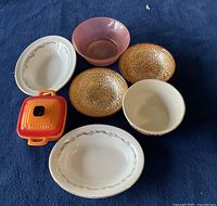 Top view of seven bowls of various types and colors laid on dark fabric.