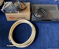 Two broadband cable modems, one on top of RCA by Thomson box, and one Motorola modem with accompanying coaxial cables and power cords on blue fabric background.