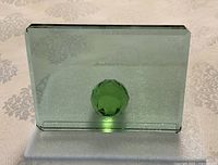 Front view of rectangular glass photo frame showing green faceted crystal sphere at bottom center