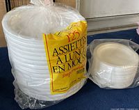 Stack of large white foam plates with yellow packaging label indicating 125 plates total.