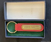 Red leather Ralph Lauren key ring inside an open box with white and green felt lining.