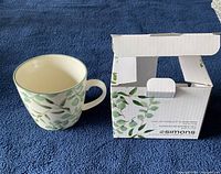 Simons ceramic cup next to its original box, showing the cup's leaf pattern and handle