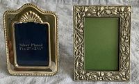 Two small picture frames side by side: left is pewter with floral design, right is silver plated with shell motif