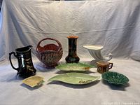 Wide view of the lot showing all nine assorted pottery and porcelain items including pitchers, planters, vases, creamers and dishes.