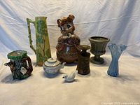 Full view of assortment of nine pottery, porcelain, and glass items on white cloth background