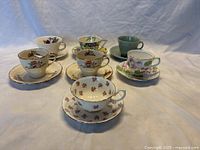 Six assorted vintage British teacups with matching saucers, showing varied floral and solid designs.