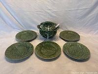 Overview of the tureen with lid and spoon surrounded by the five assorted fruit plates.