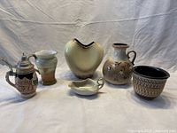 Full lot showing six ceramic and porcelain pieces including stein, vases, creamer, and small bowl