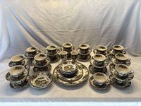 Wide view of the full set including numerous teacup & saucer sets, plates, bowls, and egg cups all arranged on a white surface with a plain white backdrop.