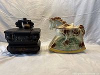 Photo of the black cook stove and hobby horse cookie jars side by side showing size and detail.